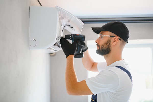 Tecnico si occupa della manutenzione stagionale di un condizionatore.